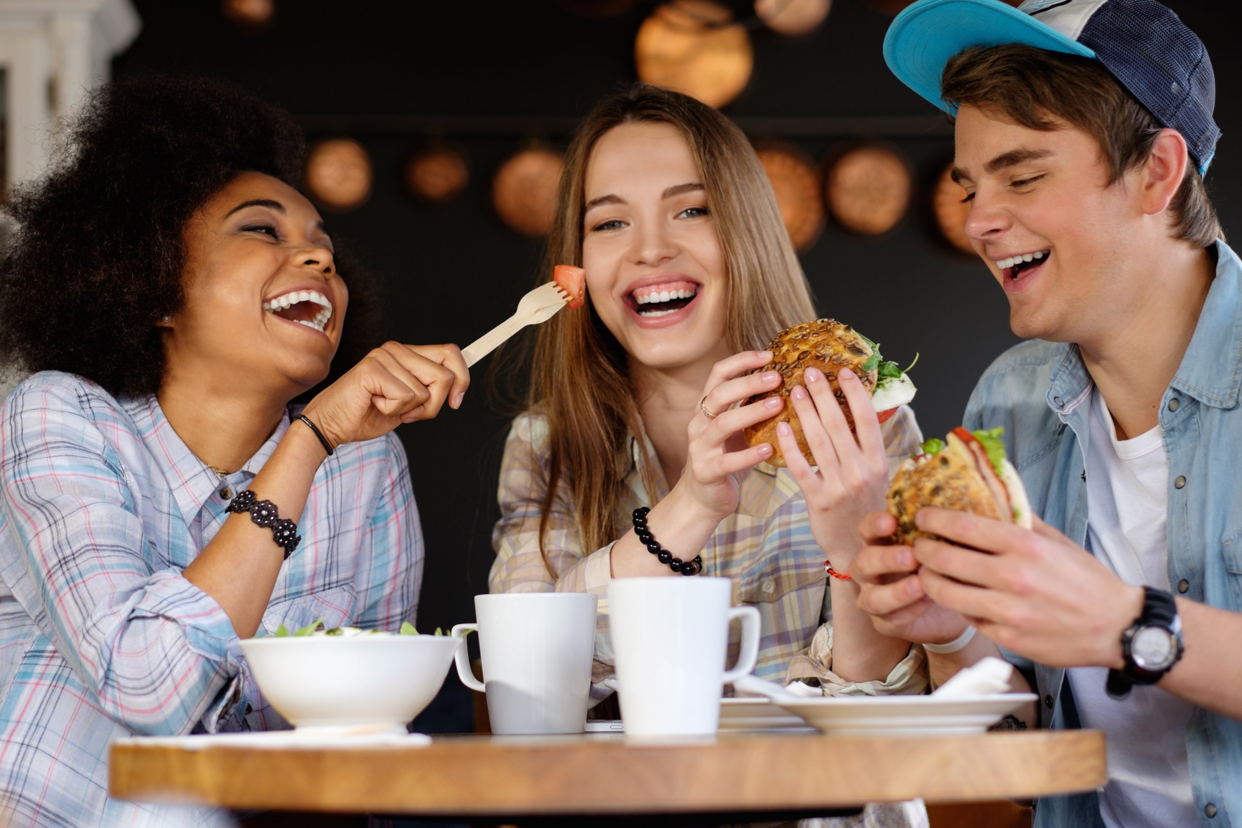 Lachende Schüler essen Burger in der Mensa 